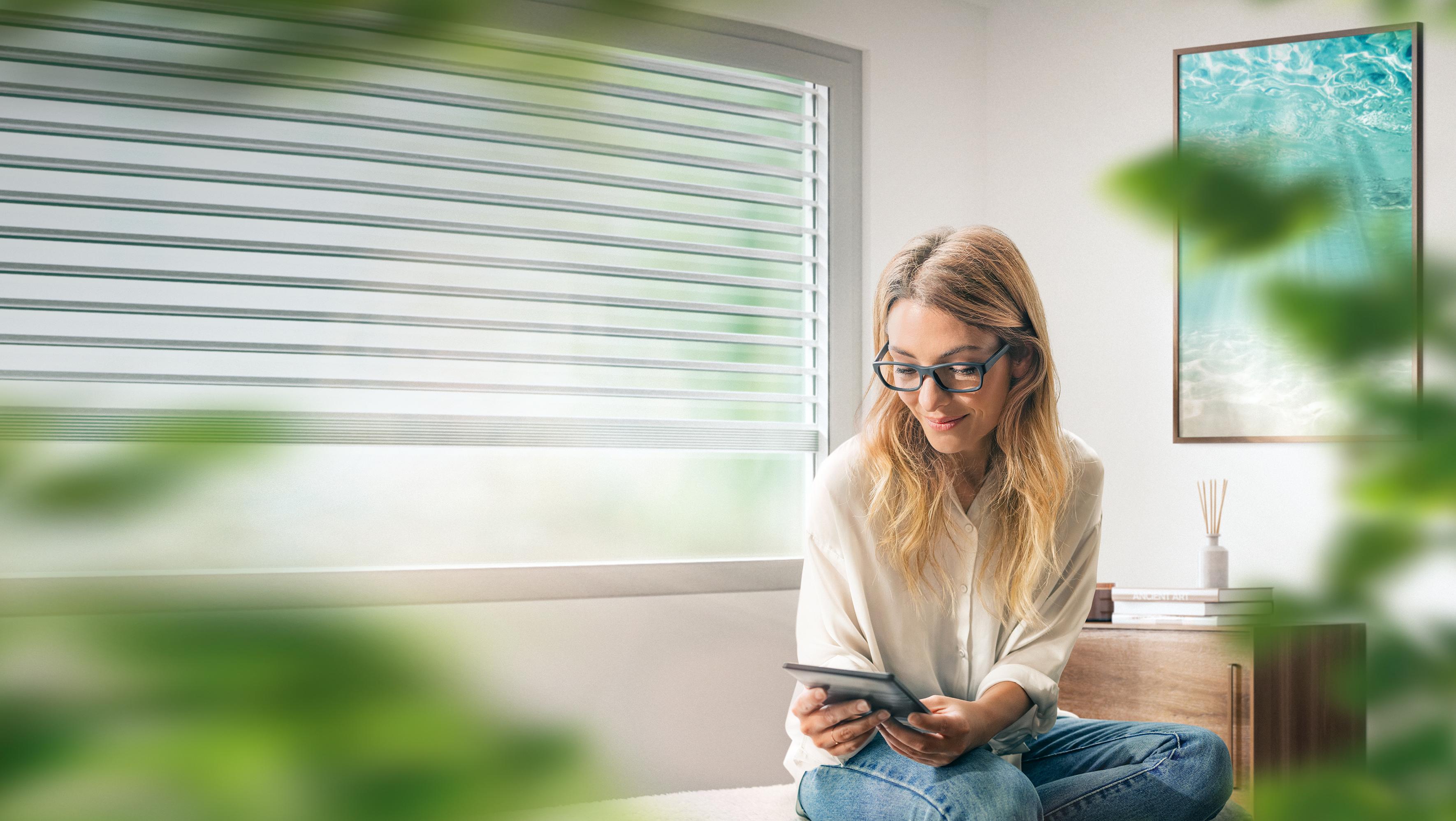 Young businesswoman with eyeglasses reading something on digital tablet in the living room